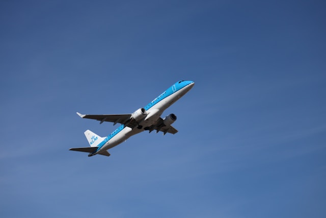 A blue and white airplane ascends into a clear sky.