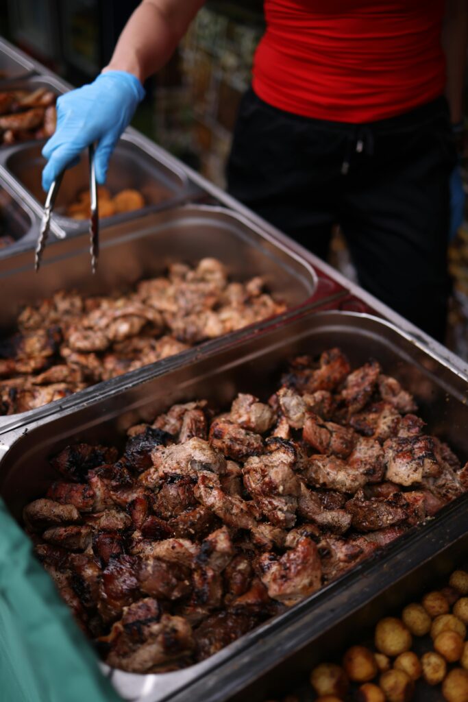 Close-up of grilled meat being served with tongs at a street food stall.